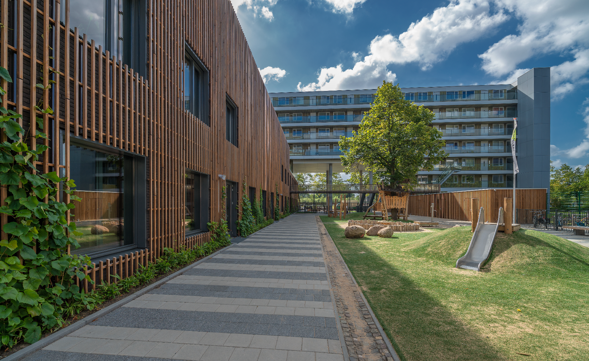 NobelWood: het hardhout alternatief voor gevels van Foreco straat langs woningen met houten gevel en glijbaan