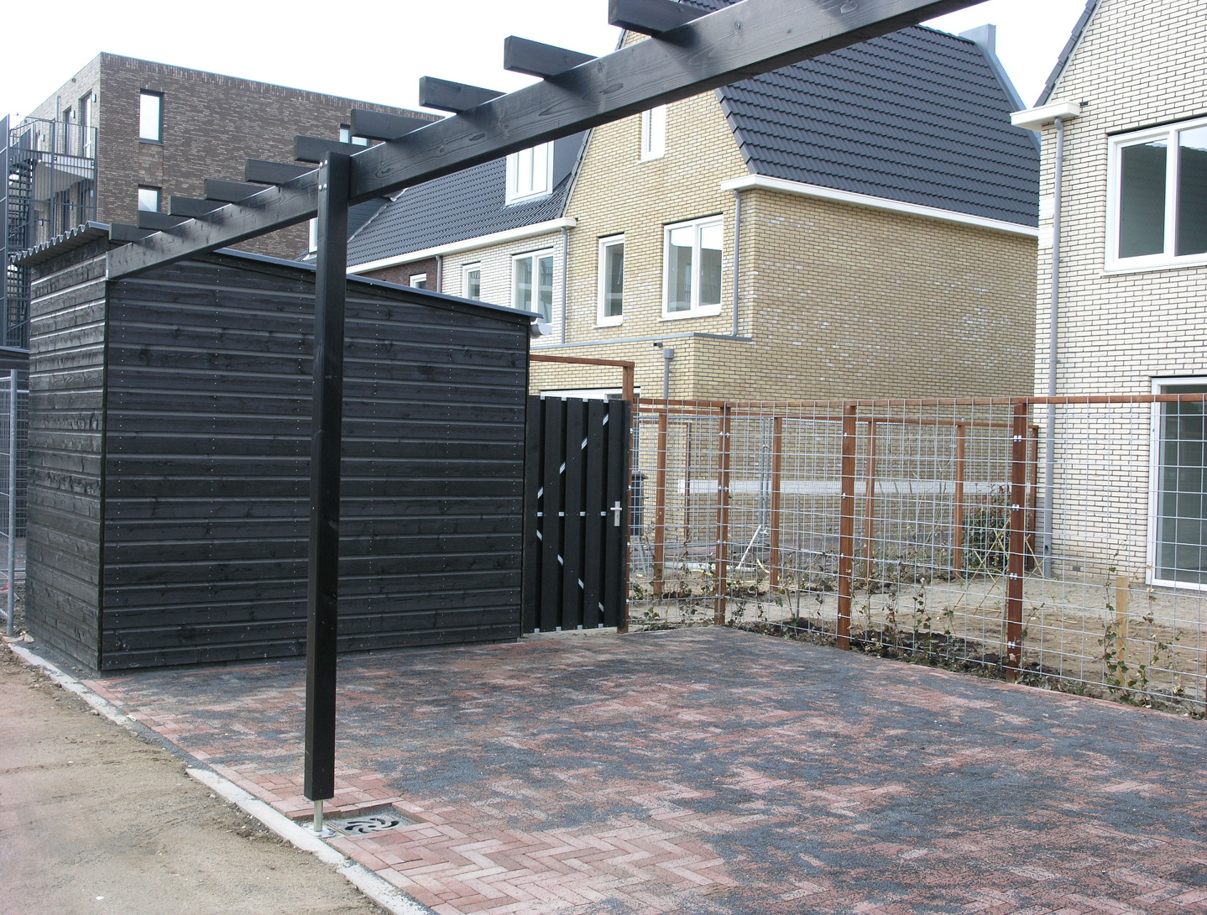 zwarte houten schuur en pergola bij woningen