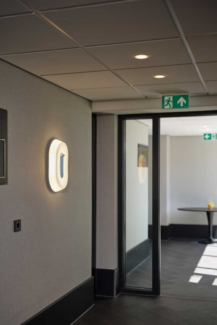 O-Lux in een gang met noodverlichting Noodverlichtingbordjes