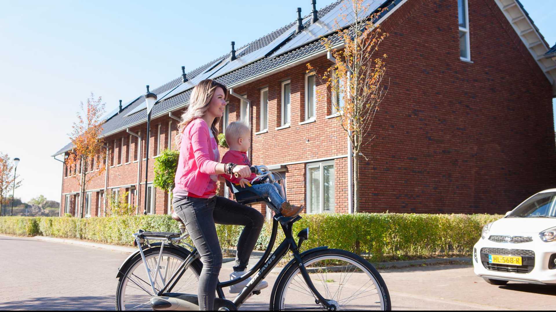 Warmtenetten hebben groot besparingspotentieel, randvoorwaarden blijven nodig Vrouw op fiets met kindje voorop in woonwijk