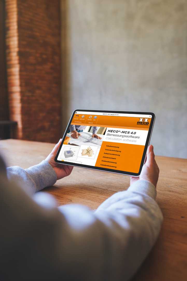 De gratis HECO Calculatiesoftware (HCS 4.0) maakt het mogelijk om verbindingen voor houtconstructies, wapening, beton en dakisolatie nauwkeurig te berekenen. iemand met tablet in handen