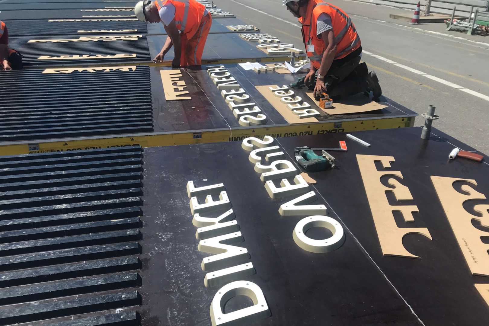 Overzicht van de twaalf wateren Bouwvakker monteert letters