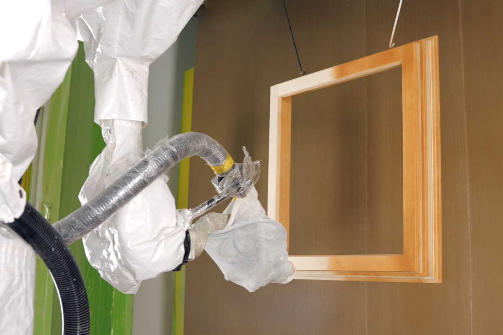 De nieuwe spuitbare grondlak Aquawood Primo RSQ van ADLER Een robot spuit verf op een kozijn