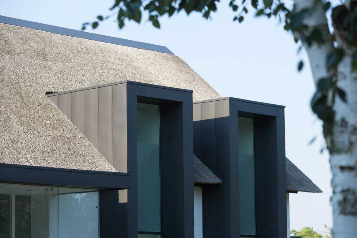 Nieuwbouw woning met rieten dak en kapellen van zink