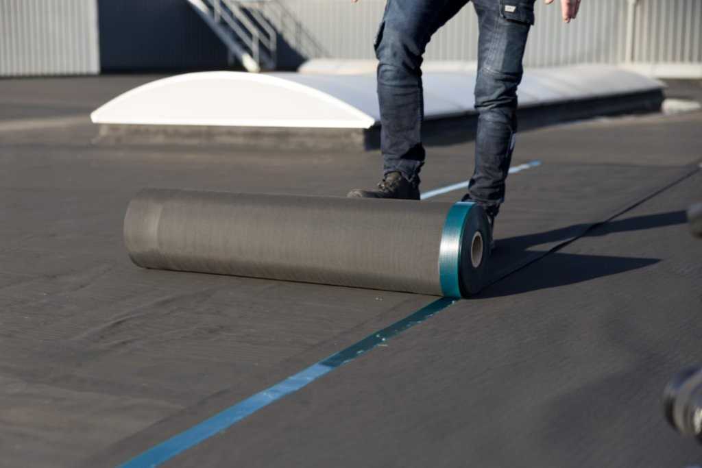 Bouwvakker rolt dakisolatiemateriaal uit