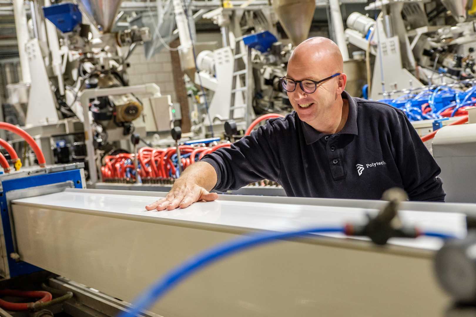 man met bril lachend naast dakrand in fabriek